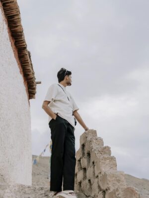Man standing on stone steps in Himachal Pradesh with mountain view.