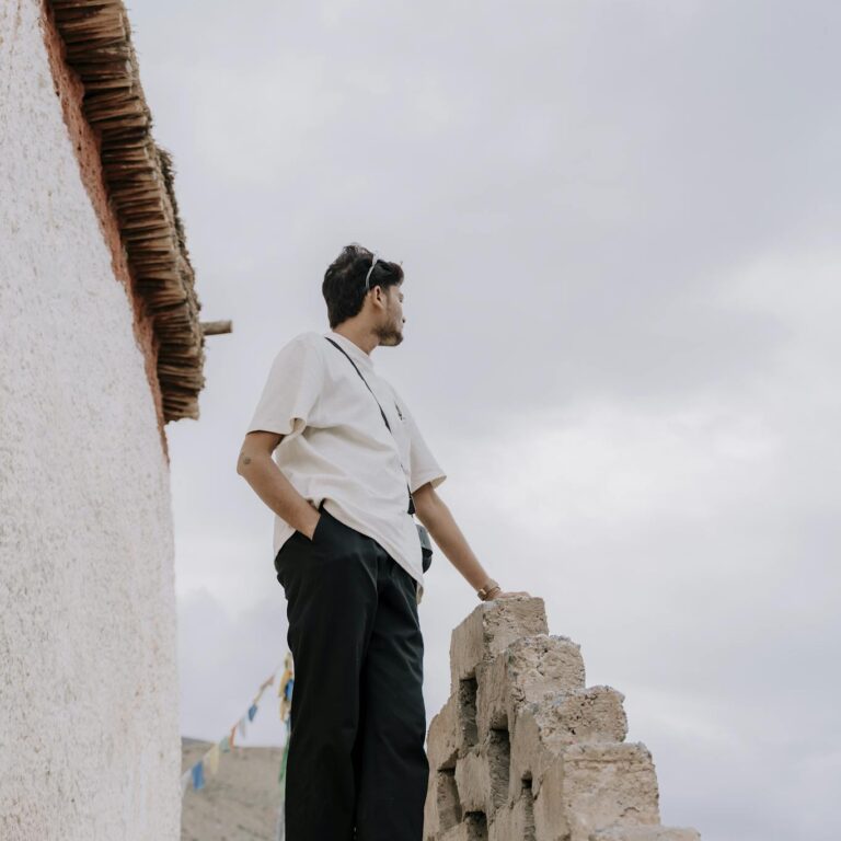 Man standing on stone steps in Himachal Pradesh with mountain view.
