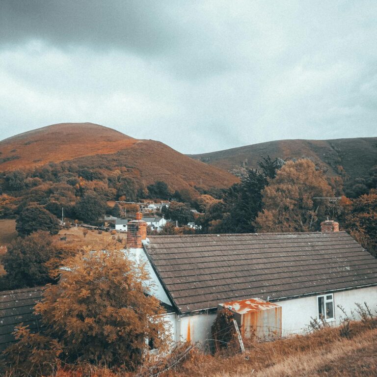 Picturesque countryside bungalow nestled among rolling hills during autumn.